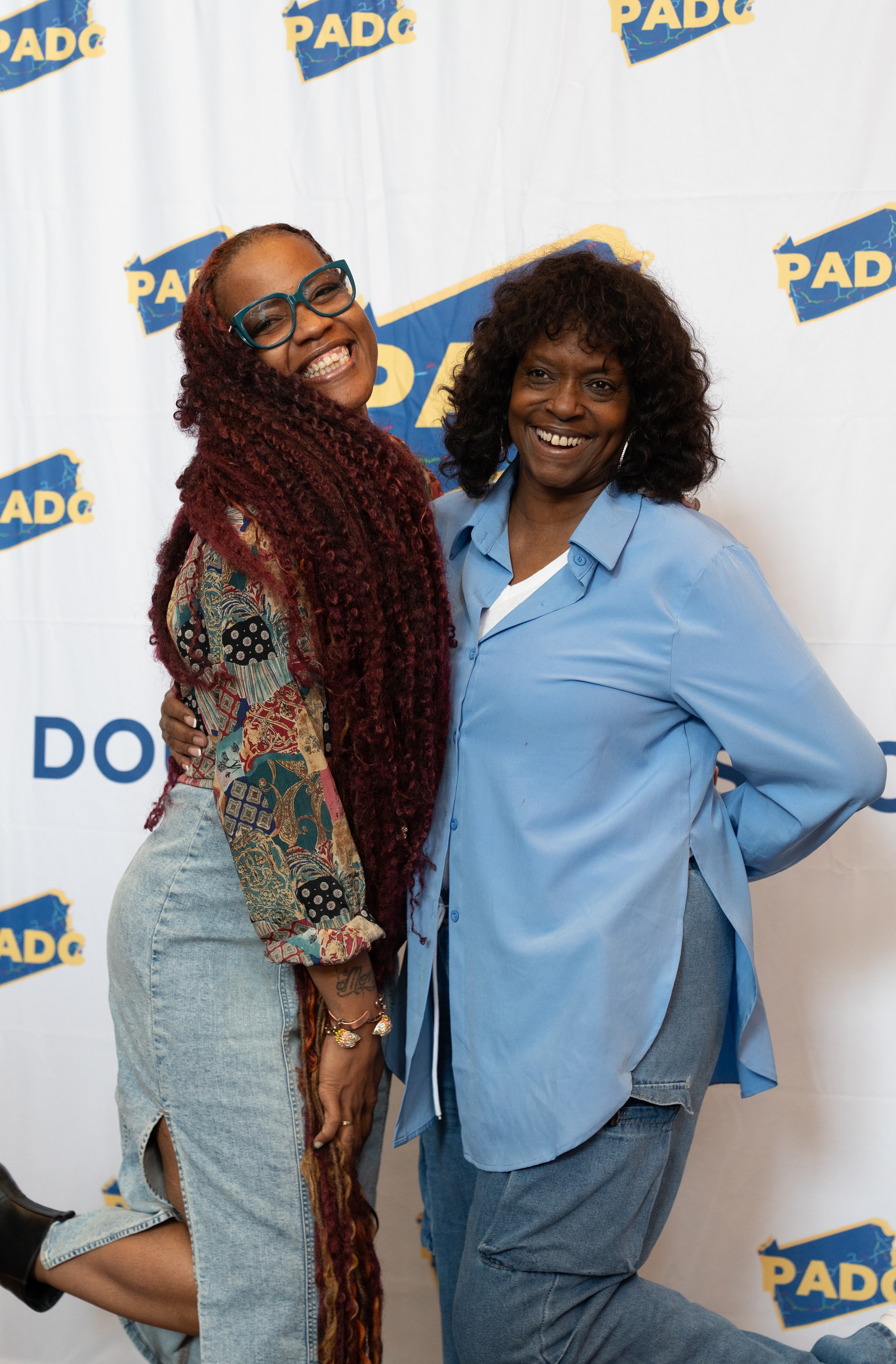 Two attendees posing in front of PADC step-and-repeat banner